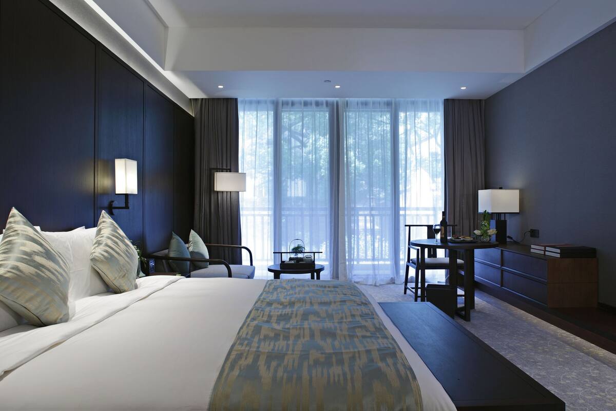 Een moderne hotelkamer met een groot bed, nachtkastjes, een bureau en een televisie.