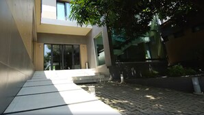 A modern building entrance with a paved pathway leading to a glass door. - Magno Suites (Malabo)