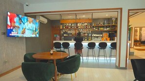 A bar area with a TV screen, bar counter, and seating arrangement. - Magno Suites (Malabo)