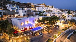 A coastal hotel with a swimming pool, white buildings, and a curved road. - Casa Grande (Mykonos)