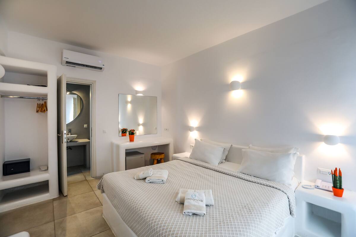 A hotel room with a bed, bedside table, and a mirror.