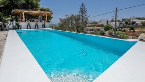 A rectangular swimming pool with clear blue water, surrounded by a white deck. - Casa Grande (Mykonos)