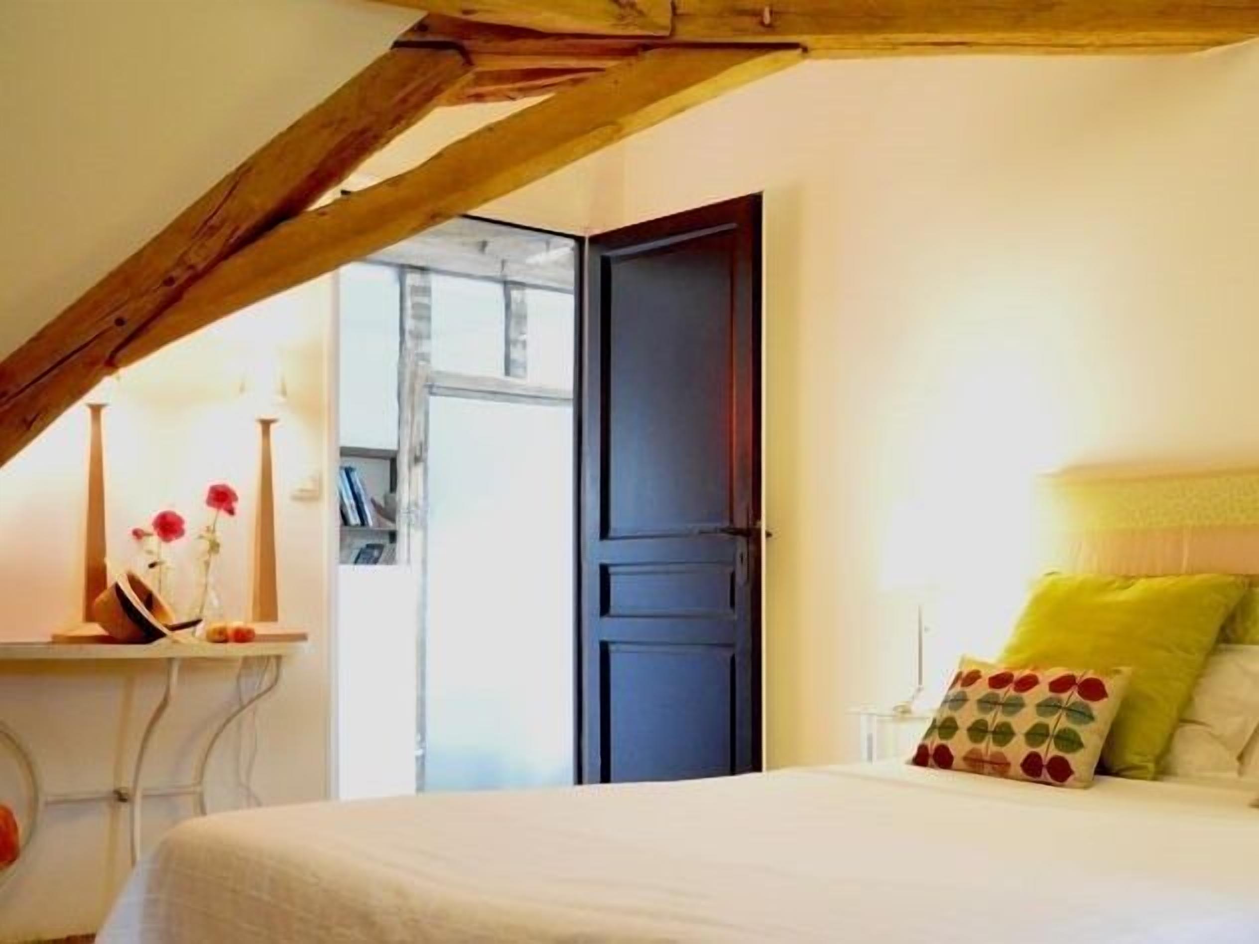 Ein Schlafzimmer mit Bett, Nachttisch, Fenster und Tür.