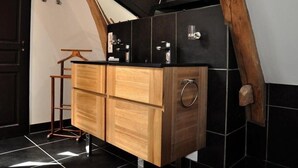 A kitchen with wooden cabinets, a black countertop, and a tiled backsplash. - La Marronnière (Cheffes)