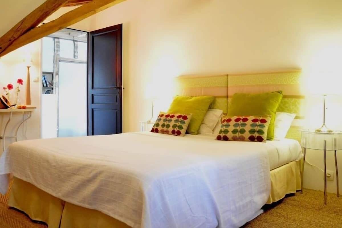 Une chambre à coucher avec un lit, une table de chevet, une lampe et une porte.