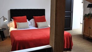 A bedroom with a bed, a nightstand, a lamp, and a wooden ceiling structure. - La Marronnière (Cheffes)