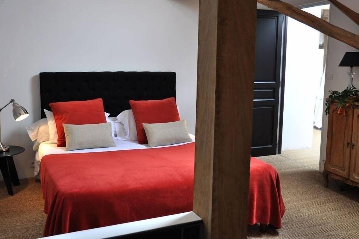 Une chambre à coucher comprenant un lit, une table de chevet, une lampe et une structure de plafond en bois.