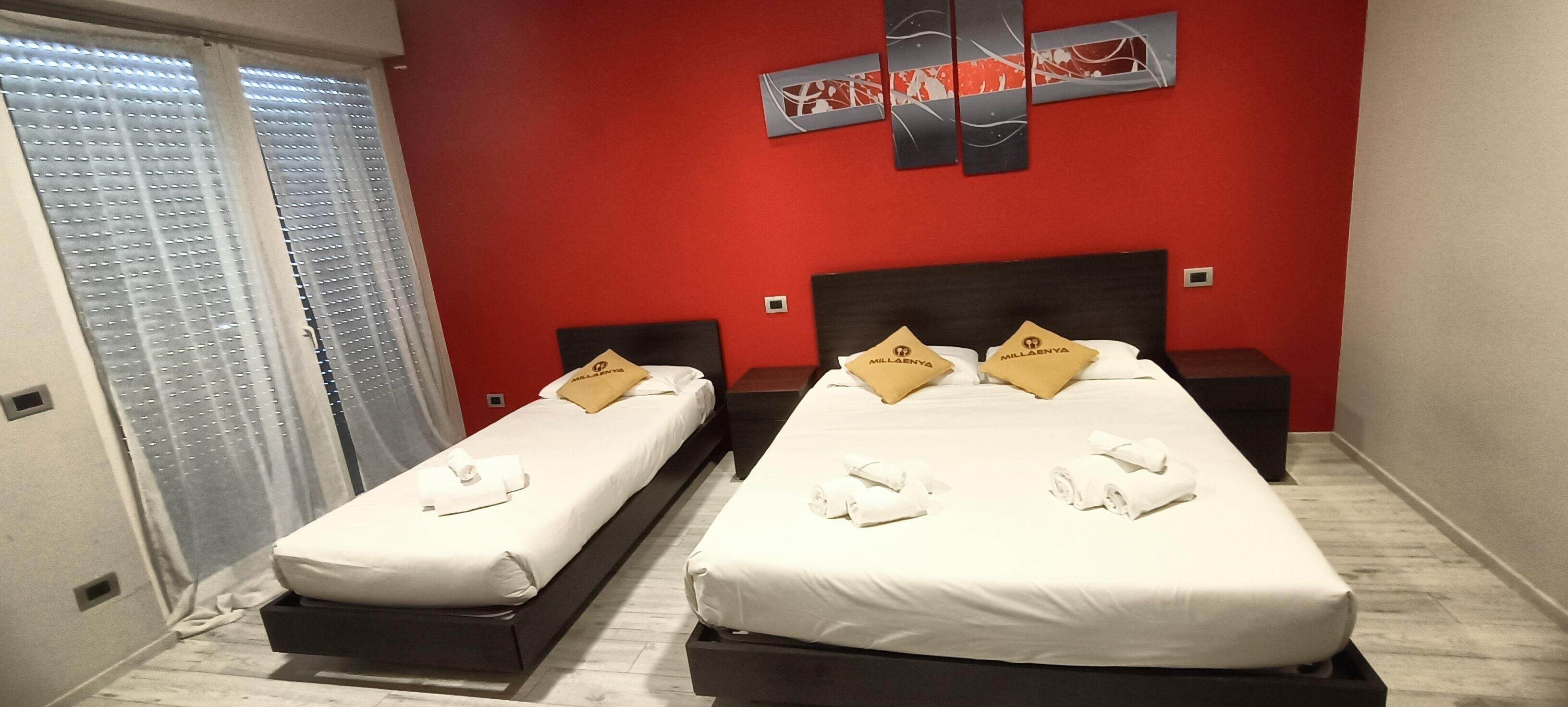 Habitación de hotel con dos camas, paredes rojas y un diseño moderno.