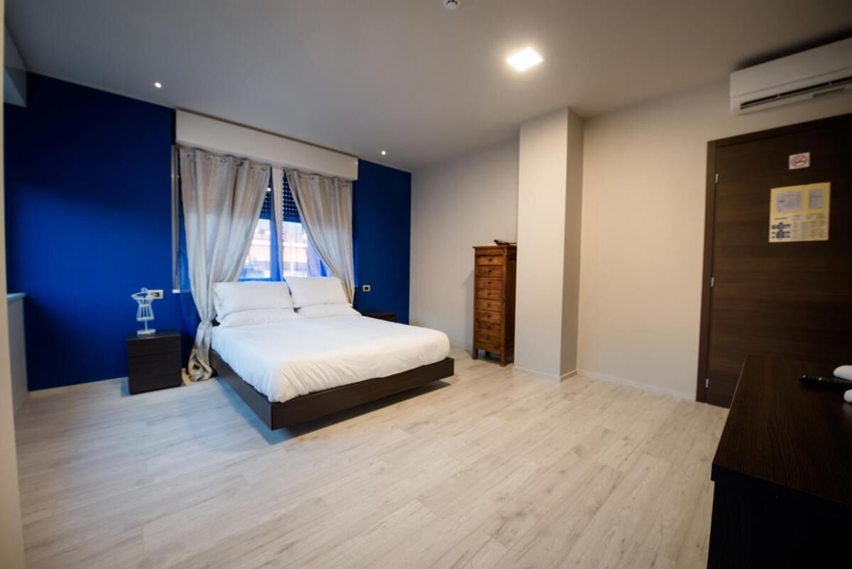 Ein Schlafzimmer mit einem Bett, einem Nachttisch, einem Holzschrank und einer Tür mit einem Schild.