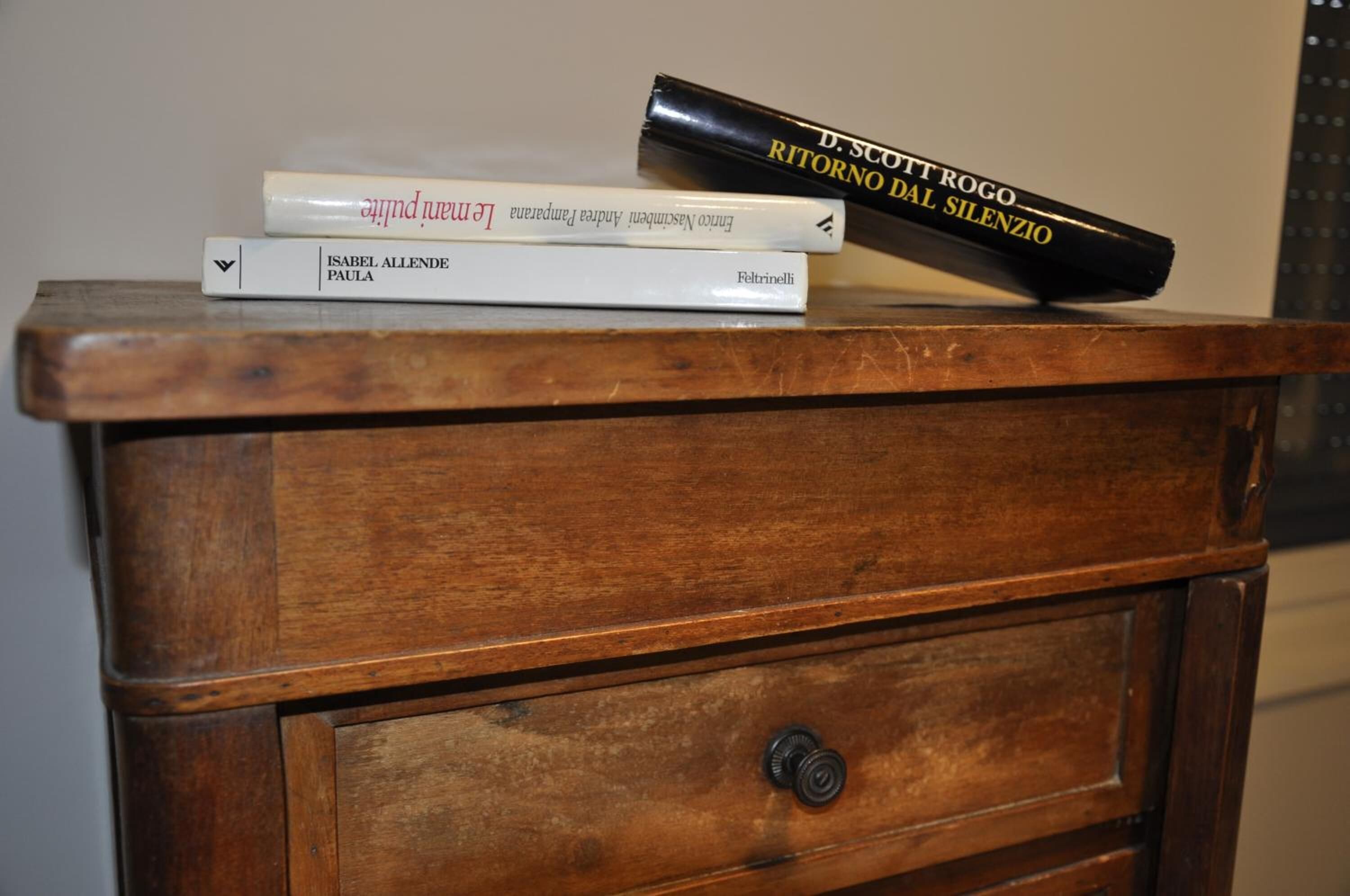 A wooden chest of drawers with three books on top.
