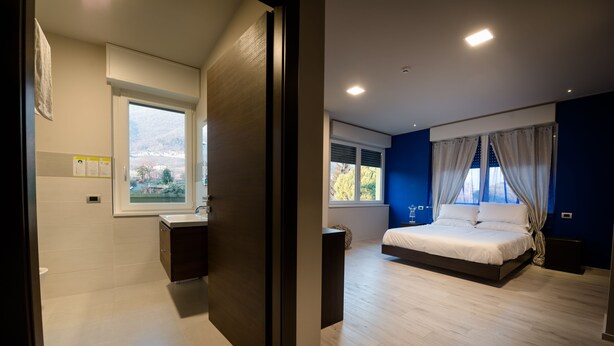 A modern bedroom with a large bed, a window with curtains, and a view of the outdoors. - Millaenya Inn (Entratico)