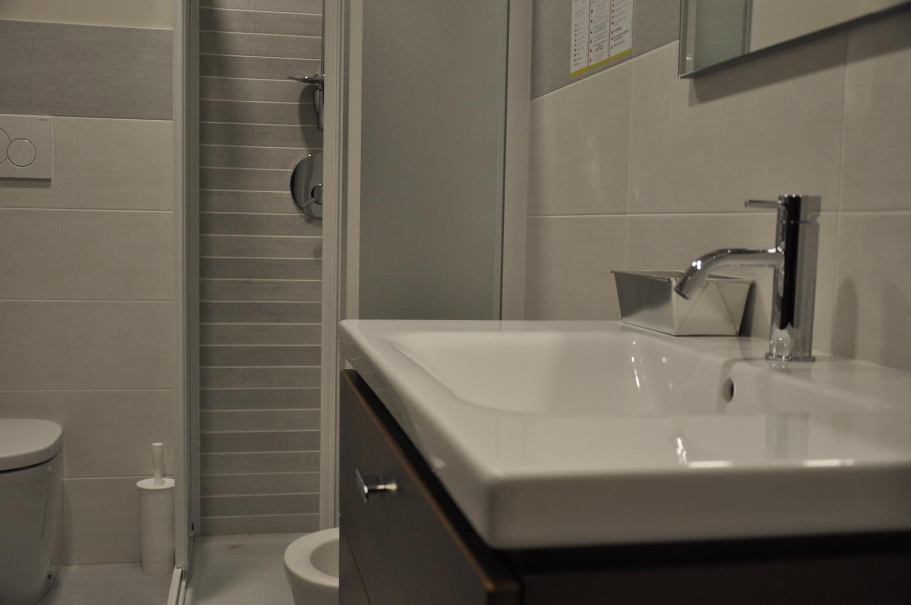 Une salle de bain avec un lavabo blanc, un miroir et des toilettes.