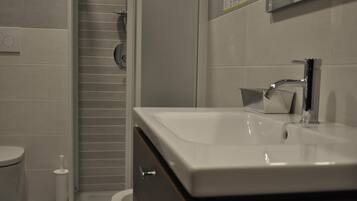 Une salle de bain avec un lavabo blanc, un miroir et des toilettes.