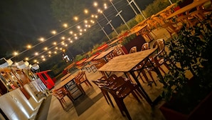 An outdoor dining area with tables and chairs, string lights overhead, and a view of the surrounding landscape. - Millaenya Inn (Entratico)