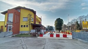 A multi-story building with a yellow and red facade, a staircase leading to the entrance, and a sign indicating a restaurant, grill, and pizzeria. - Millaenya Inn (Entratico)