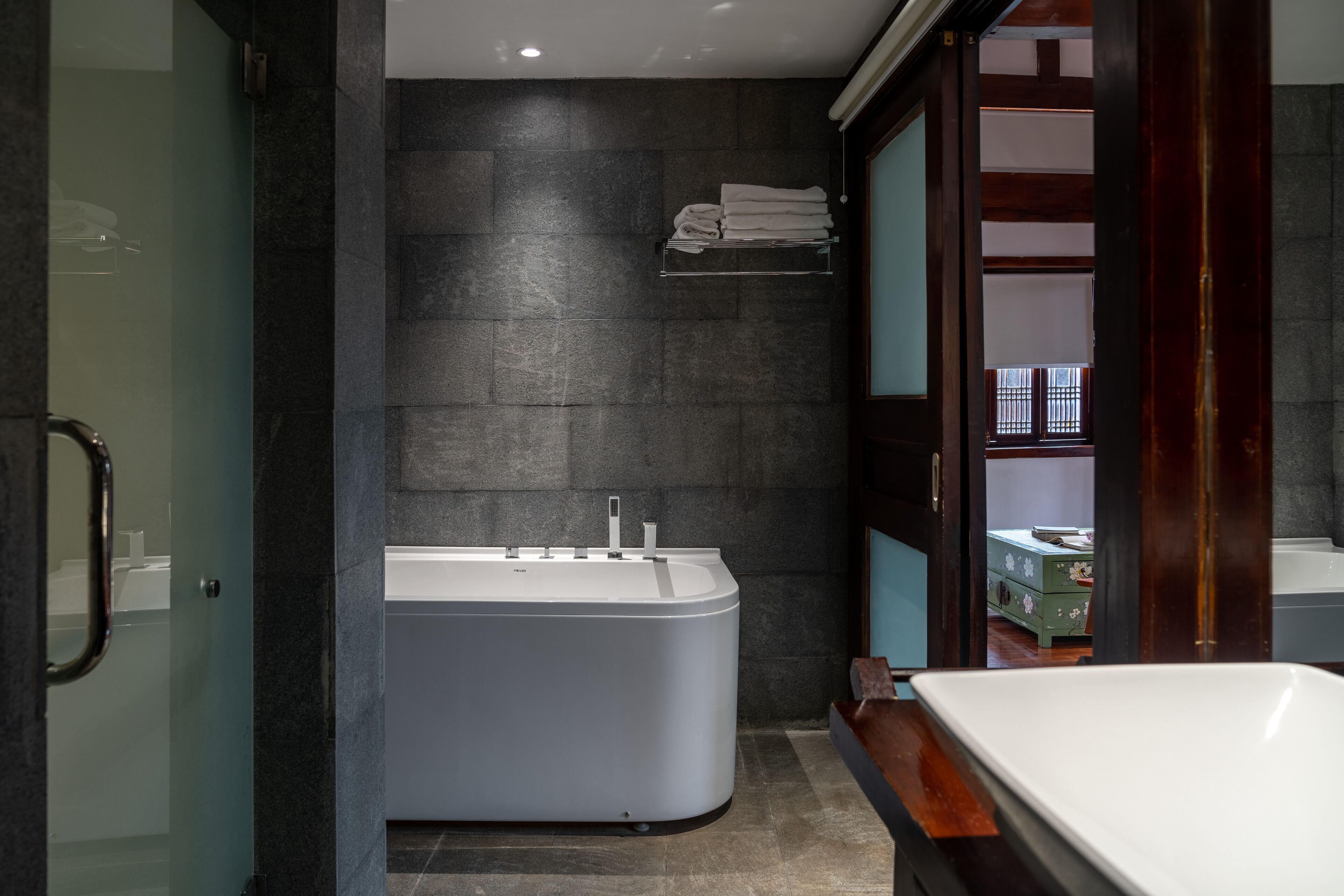 A modern bathroom with a freestanding bathtub, a glass shower enclosure, and a wooden vanity.
