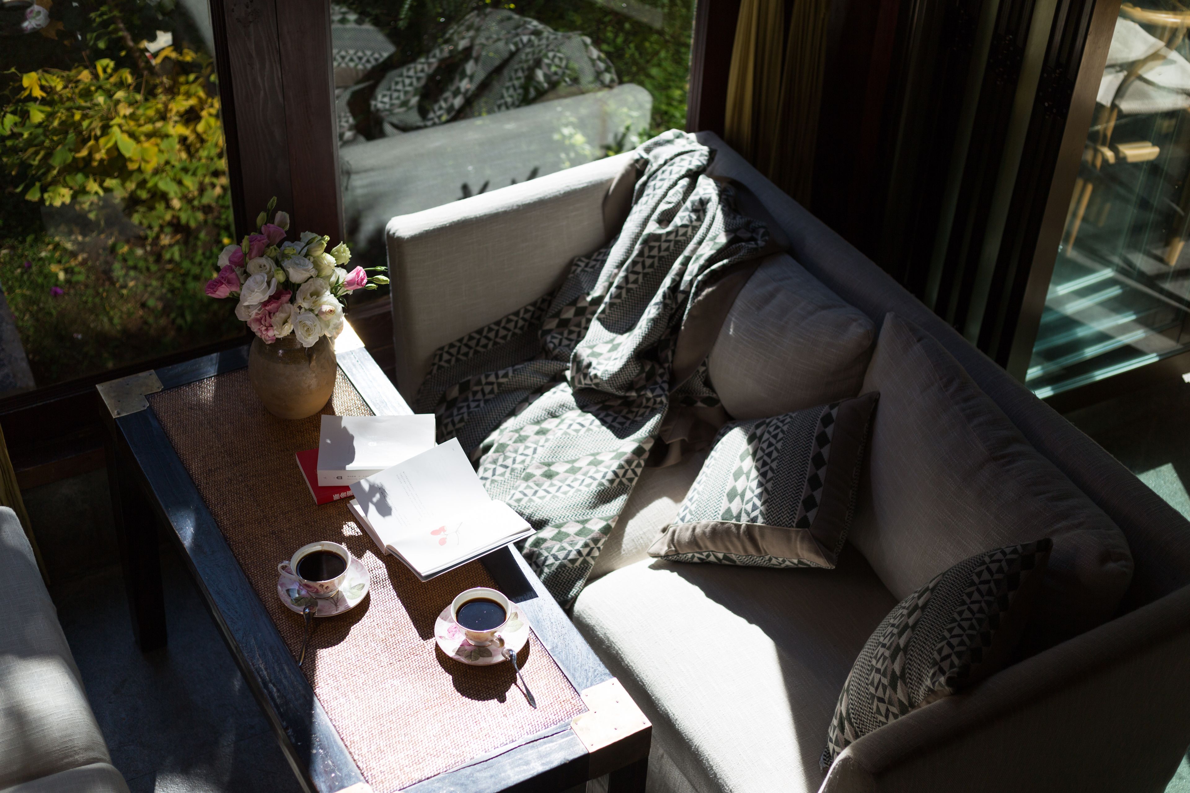 Una habitación iluminada por el sol con un sofá, una mesa de centro y un jarrón con flores.