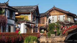 Traditional buildings with a reflection in the water, a stone bridge, and a clear sky. - Lijiang Hotel JunPoXuan (Lijiang)