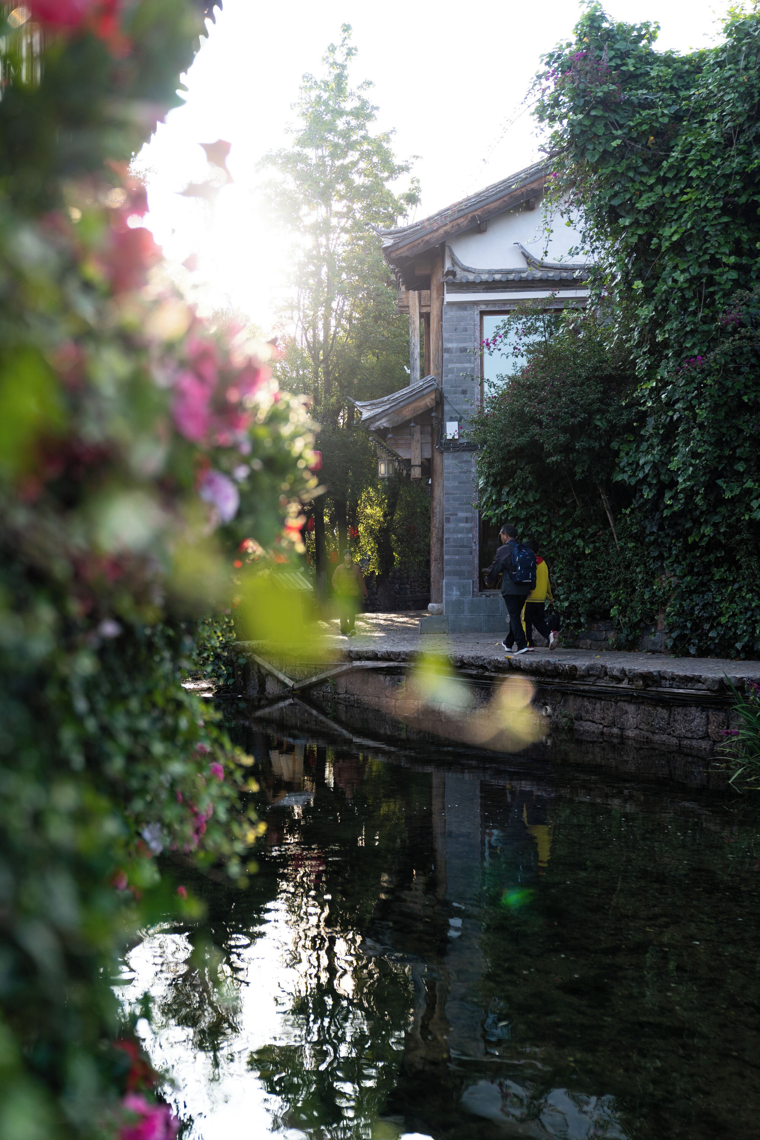 A traditional building with a stone pathway and a water body in front.