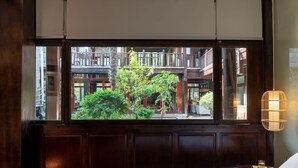 A hotel room with a large window, wooden paneled walls, a bed with patterned bedding, and a bedside lamp. - Lijiang Hotel JunPoXuan (Lijiang)