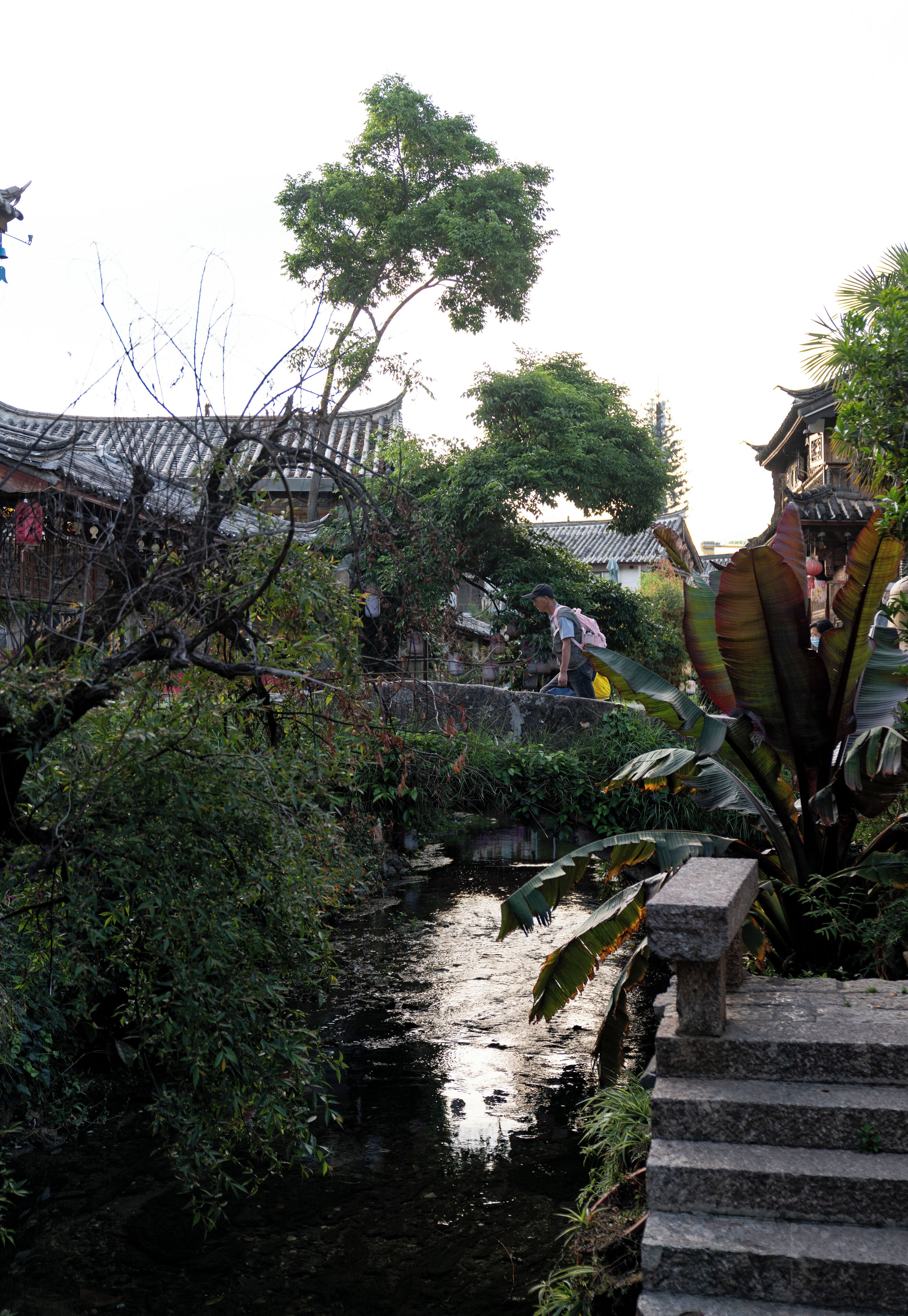 A traditional building with a tiled roof, a stone staircase, and a small waterway.