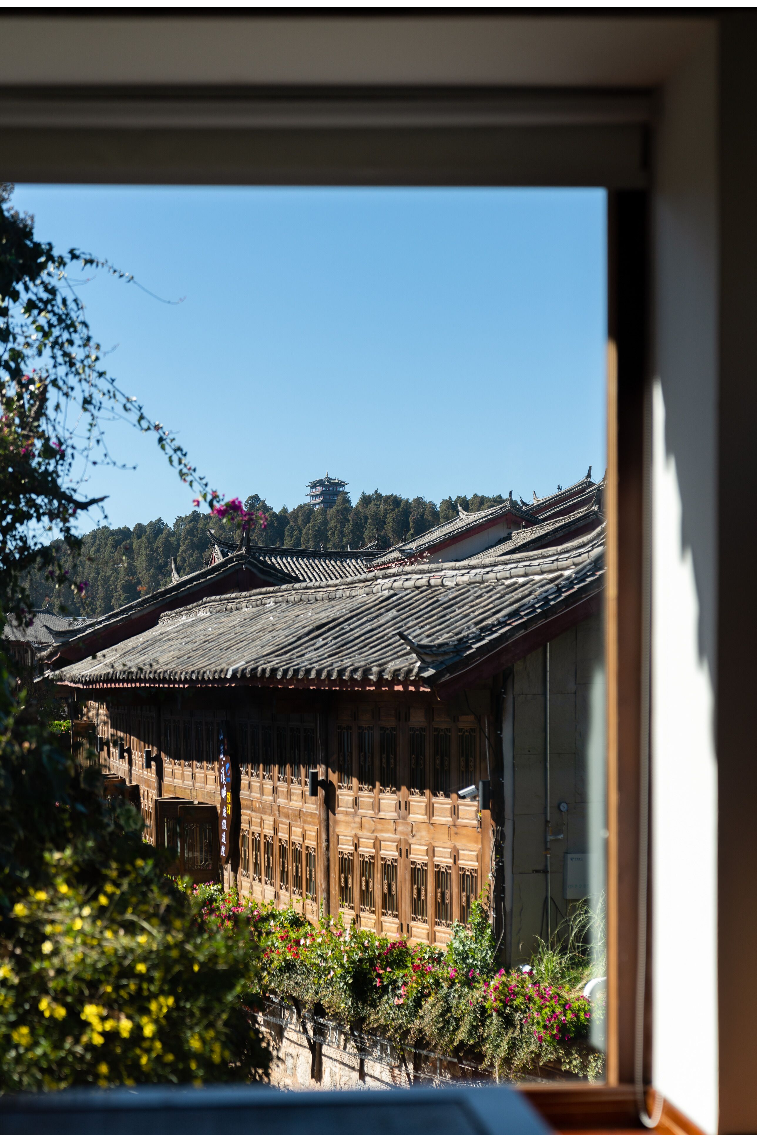Ein Gebäude im traditionellen Stil mit Ziegeldach und Holzkonstruktion, wie durch ein Fenster zu sehen.