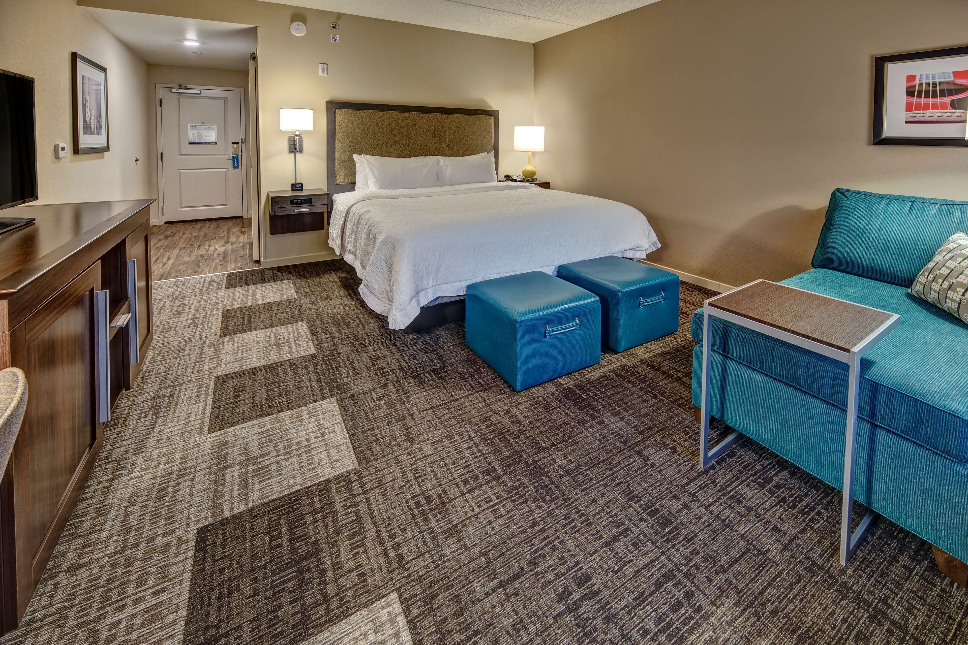A hotel room with a bed, a desk, a sofa, and a small table.