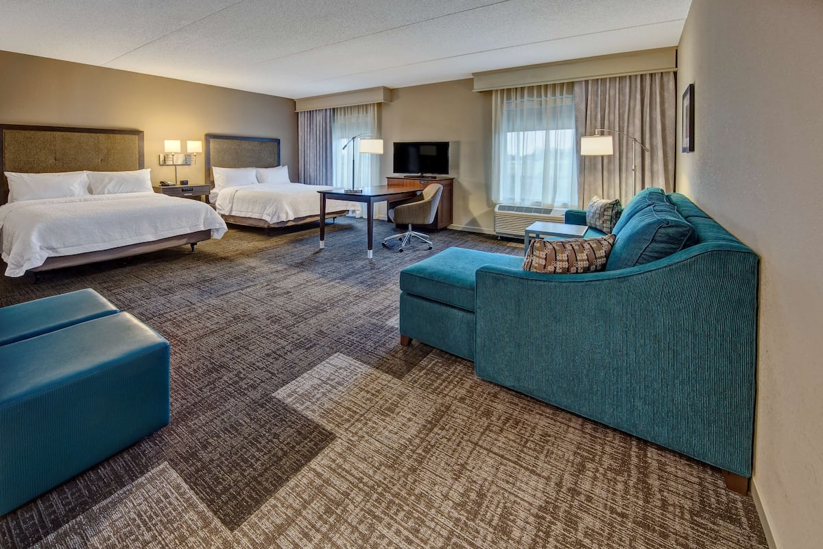 Une chambre d’hôtel avec deux lits, un bureau, une télévision, un canapé et une petite table.