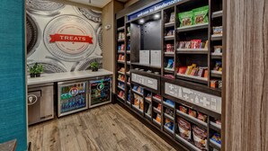 Un bar proposant des collations, avec une enseigne indiquant « Friandises », des distributeurs automatiques et des étagères remplies de snacks et de boissons.