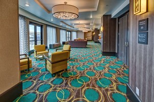 Un hall de hotel con alfombra estampada, una zona de estar y un mostrador de recepción.