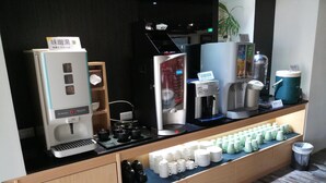 A coffee station with various coffee machines and a display of disposable cups. - Tapeng Bay Holiday Hotel (Donggang)