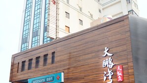 A building with a sign for 'Watsons' and 'Tapeng Bay Holiday Hotel'. - Tapeng Bay Holiday Hotel (Donggang)