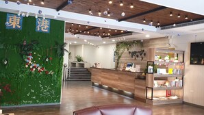 A reception area with a green wall, wooden reception desk, and a staircase leading to upper floors. - Tapeng Bay Holiday Hotel (Donggang)