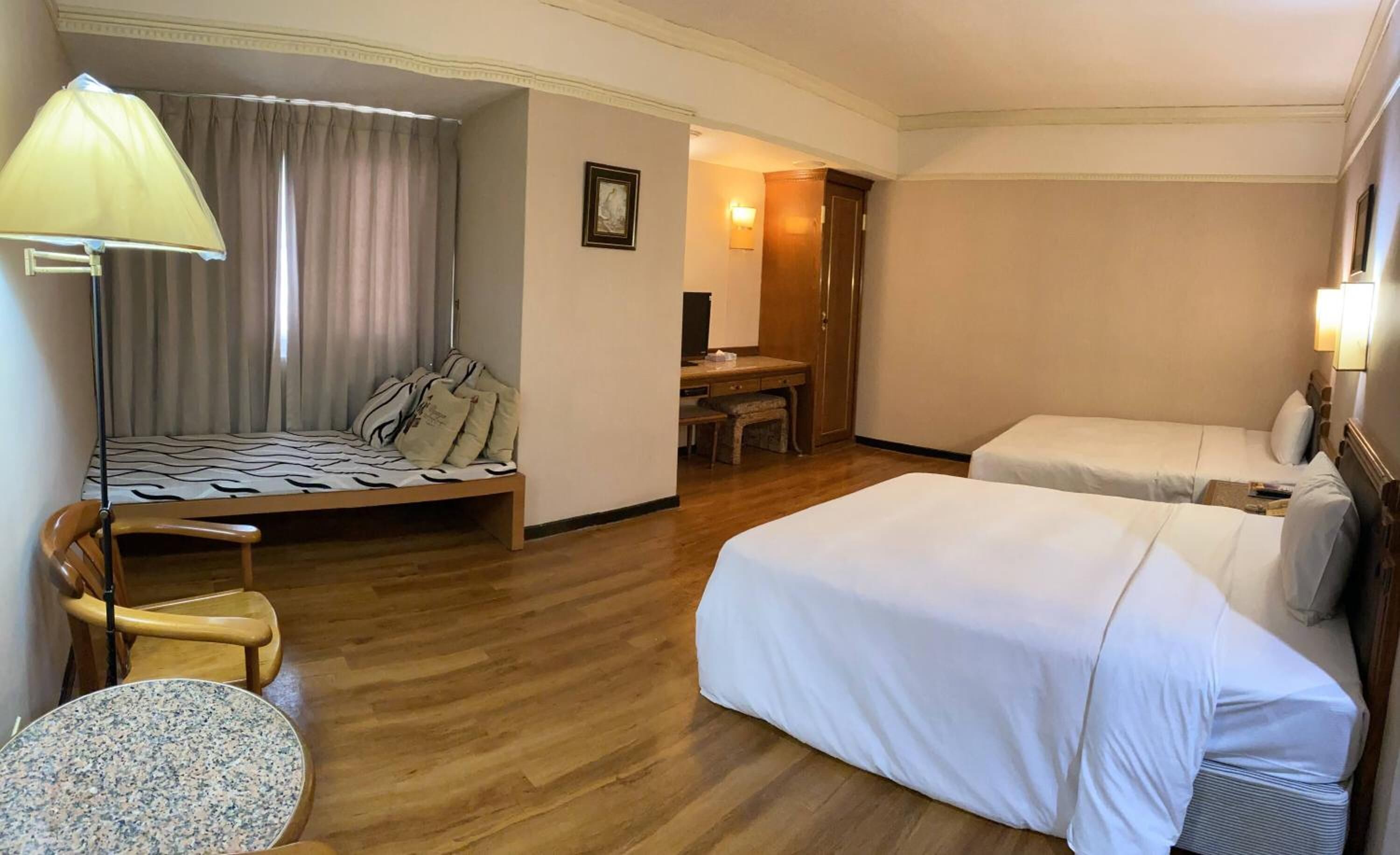 Una habitación de hotel con cama, escritorio, silla y lámpara.