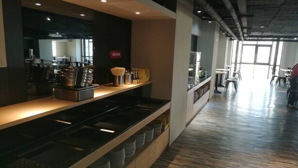 A modern kitchen area with stainless steel appliances, a long counter, and neatly stacked plates. - Tapeng Bay Holiday Hotel (Donggang)