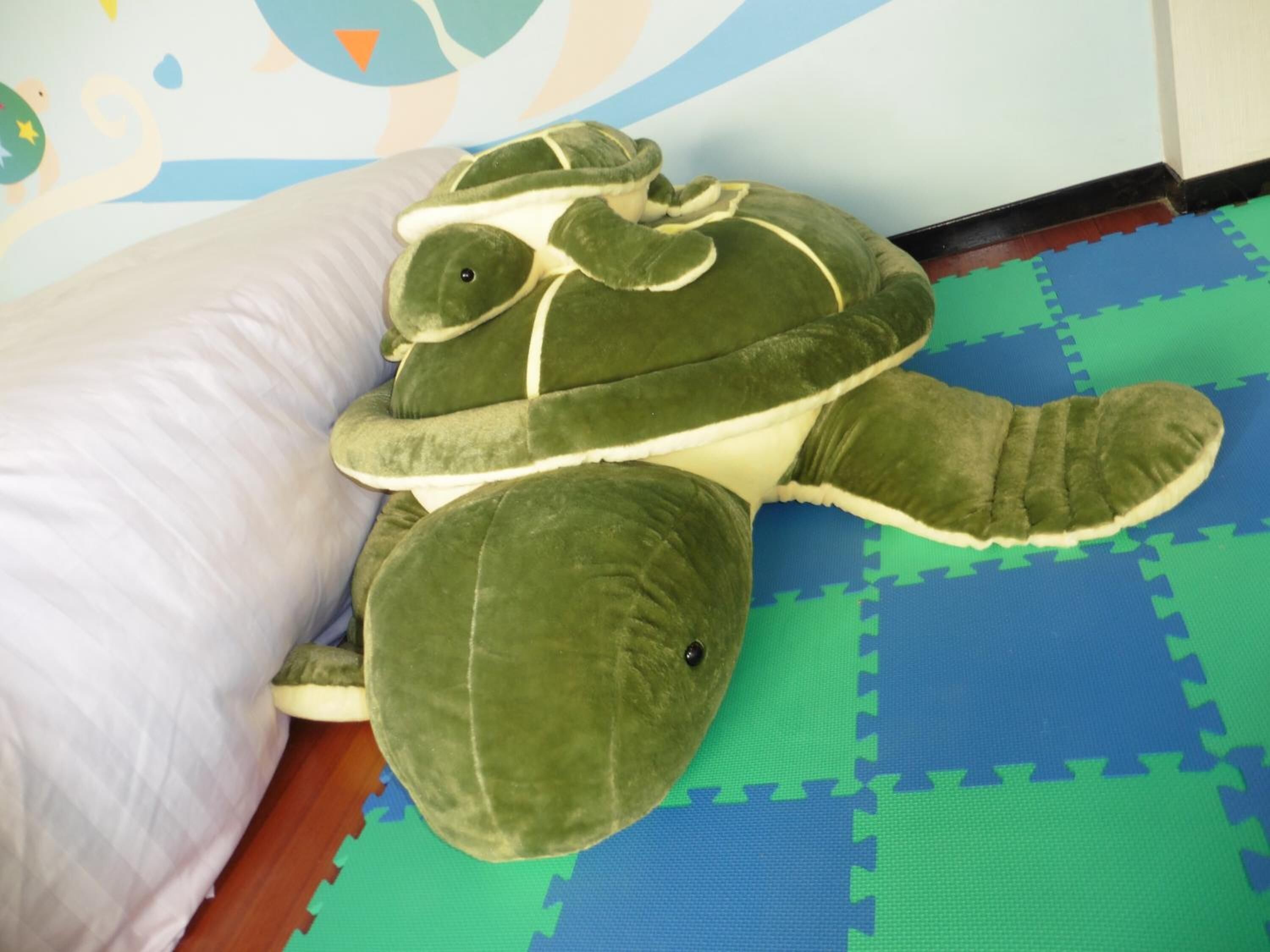 Um brinquedo de tartaruga macia sobre um tapete de espuma azul e verde.