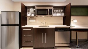 Una cocina compacta con un refrigerador de acero inoxidable, un microondas y un lavavajillas.