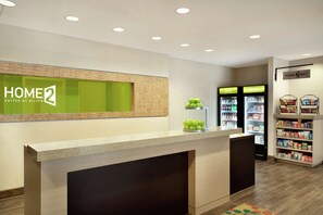A hotel reception area with a counter, a green-framed window, and a sign reading "HOME 2 SUITES BY HILTON". - Home2 Suites by Hilton Middletown (Middletown)