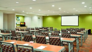 A conference room with multiple tables and chairs, a projector screen, and a green accent wall. - Home2 Suites by Hilton Middletown (Middletown)