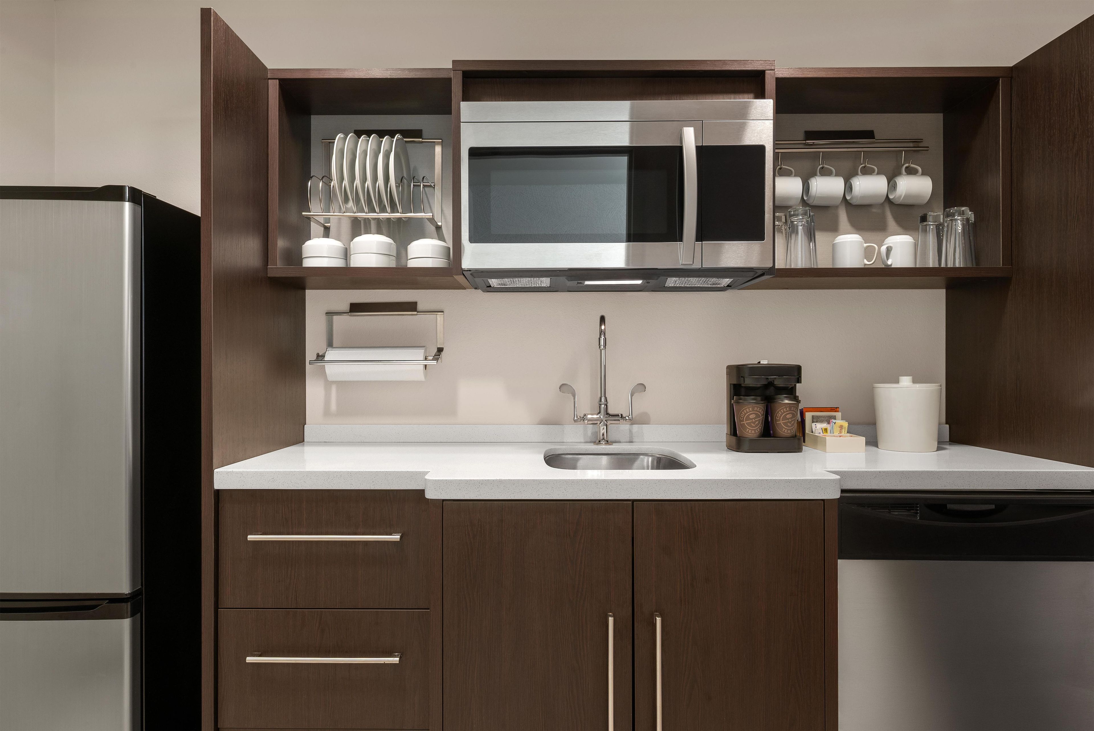 Una cocina moderna con un refrigerador de acero inoxidable, un microondas y una cafetera.