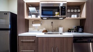 Una cocina compacta con un refrigerador de acero inoxidable, un microondas y una cafetera.