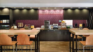 A modern restaurant with a central island, multiple tables, and chairs. - Home2 Suites by Hilton Middletown (Middletown)