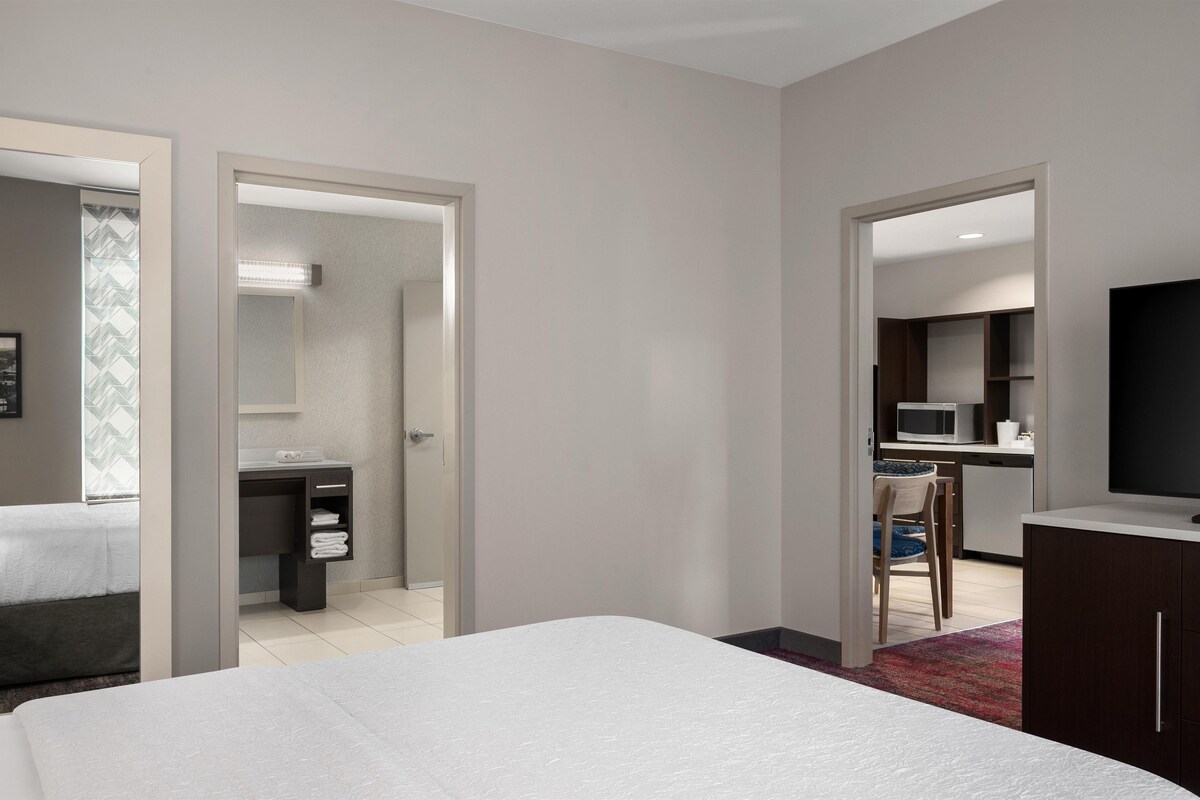 A hotel room with a bed, a desk, a chair, and a TV.