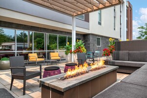 Un espacio al aire libre con patio amoblado, una chimenea y vistas de los edificios circundantes.