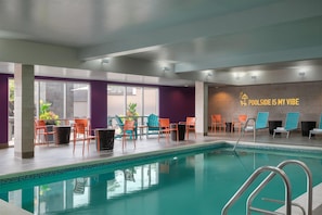 An indoor swimming pool area with chairs and a sign that reads 'POOLSIDE IS MY VIBE'. - Home2 Suites by Hilton Middletown (Middletown)