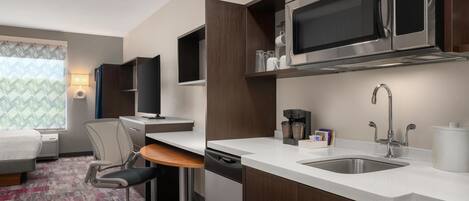Une chambre d’hôtel équipée d’une kitchenette comprenant un four à micro-ondes, une machine à café et un évier.