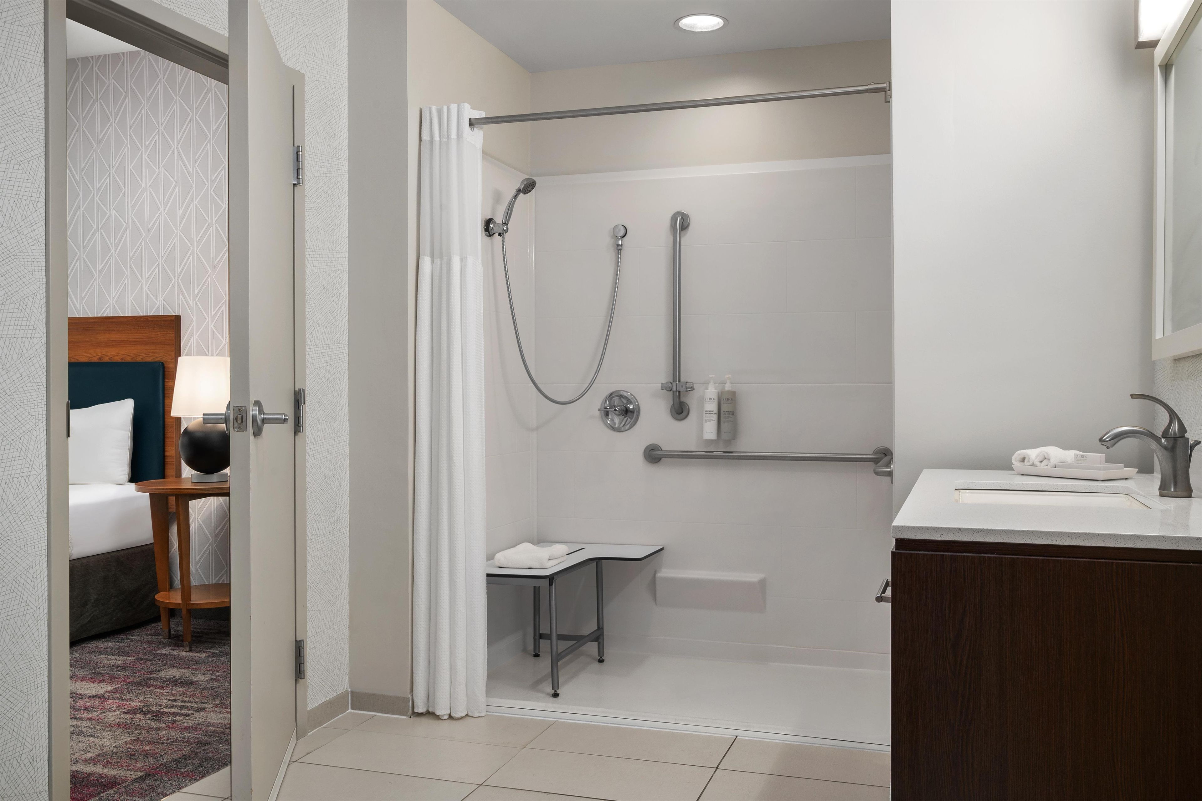 Een moderne badkamer met een douche, een wastafel en een klein tafeltje met een handdoek.