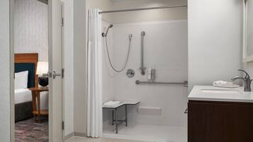 Een moderne badkamer met een douche, een wastafel en een klein tafeltje met een handdoek.