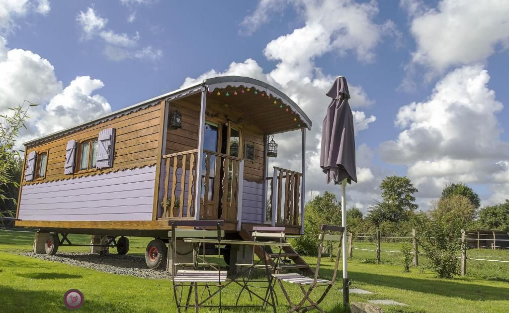 Una casa de madera con un porche cubierto y una pequeña mesa y sillas dispuestas afuera.