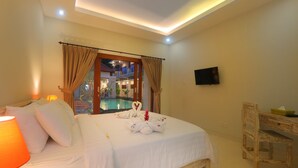 Une chambre avec un lit, un bureau, une télévision et une vue sur une piscine et un espace extérieur.